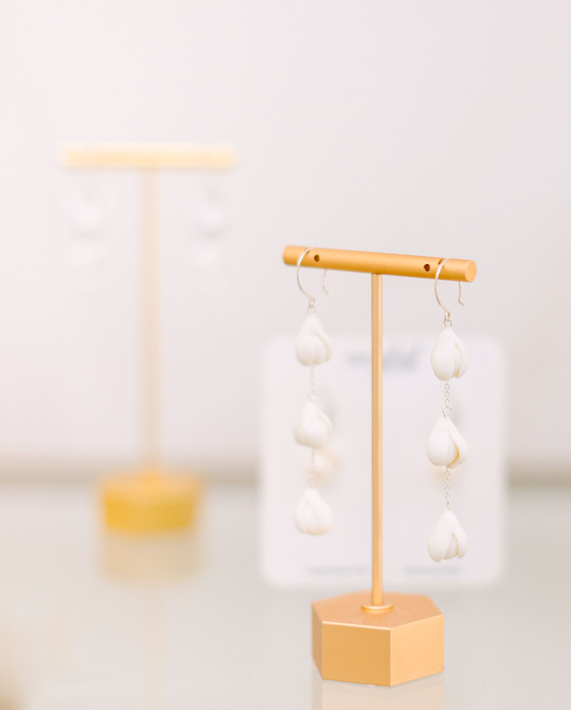 A pair of earrings sitting on top of a gold display stand on a table.