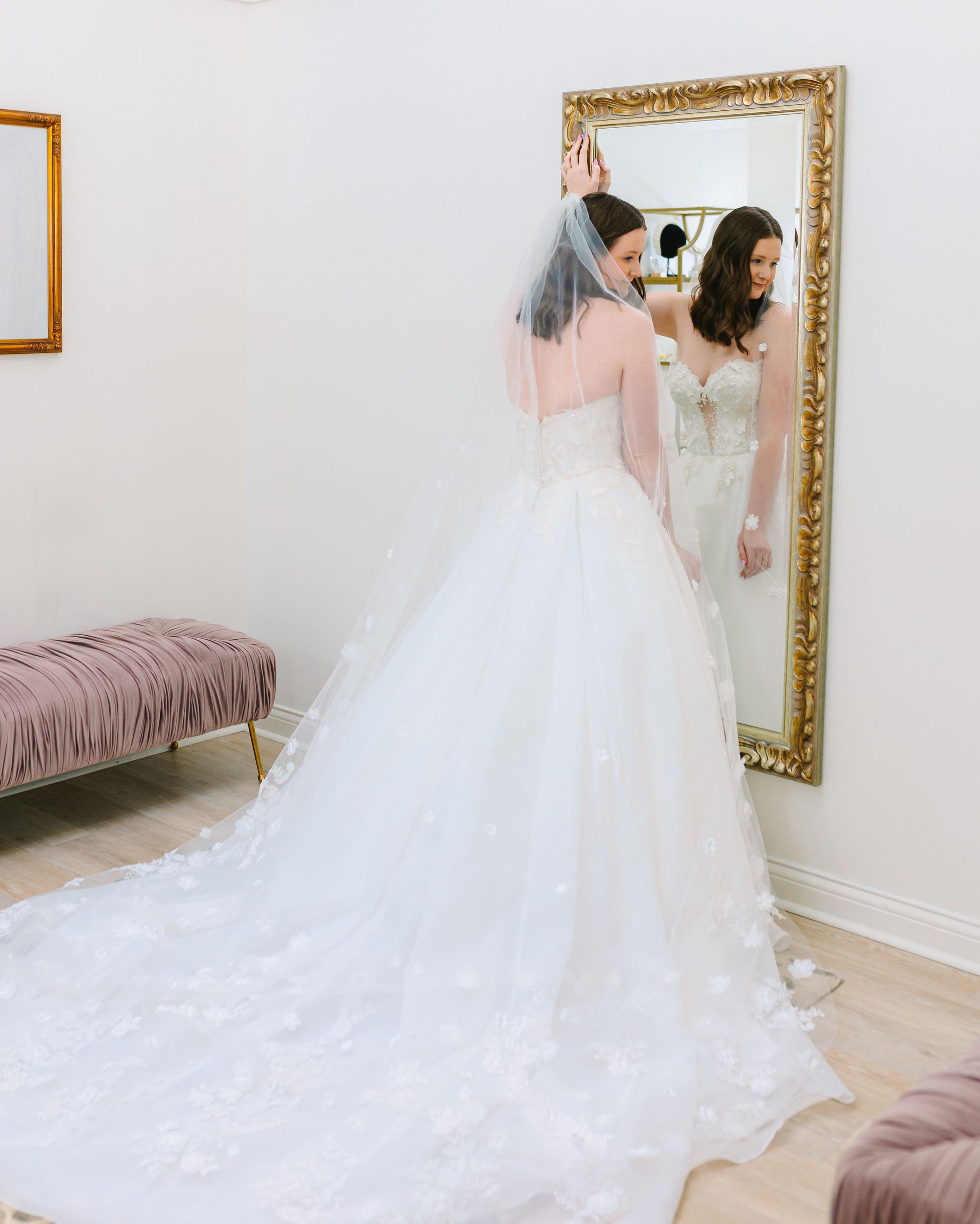 A woman in a wedding dress is standing in front of a mirror.
