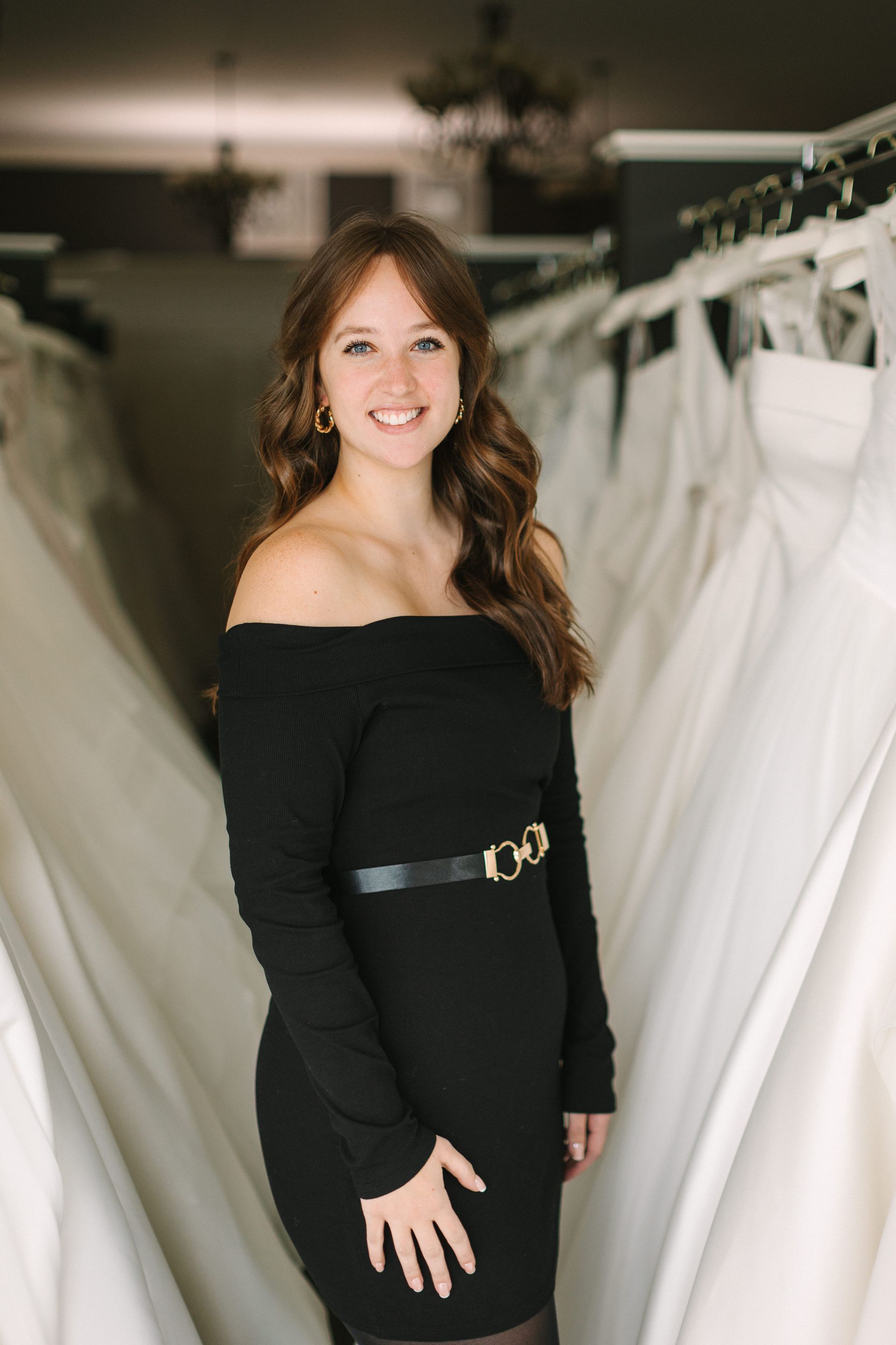A woman in a white shirt is sitting on a brown couch.