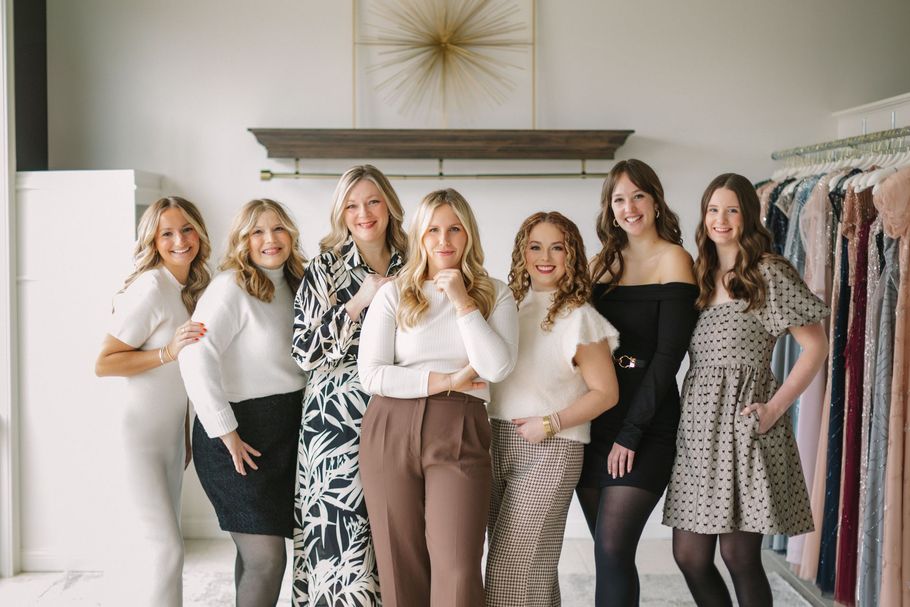 A group of women are posing for a picture in a clothing store.