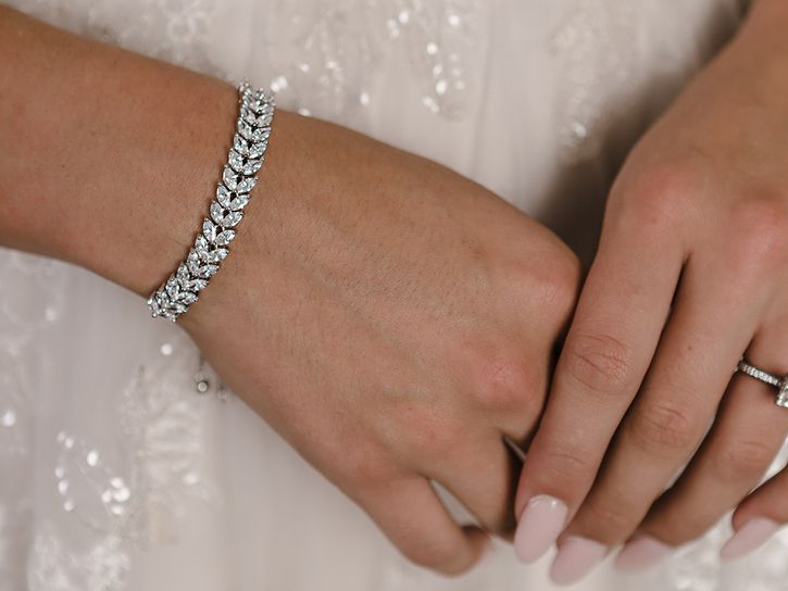 A woman wearing a bracelet and a wedding ring on her wrist.