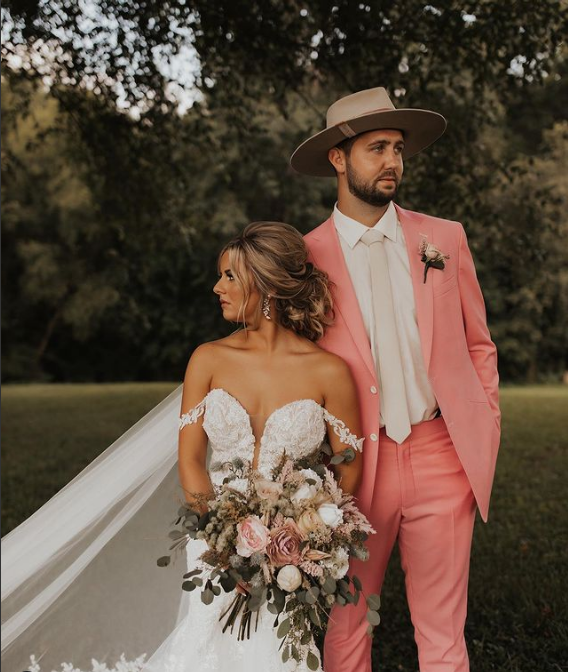 A bride and groom standing next to each other in a field