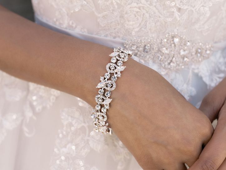 A woman in a wedding dress is wearing a bracelet on her wrist.