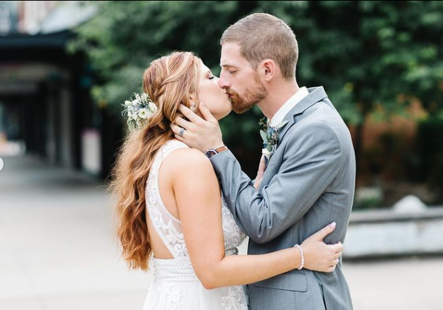 A bride and groom are kissing in front of a building.