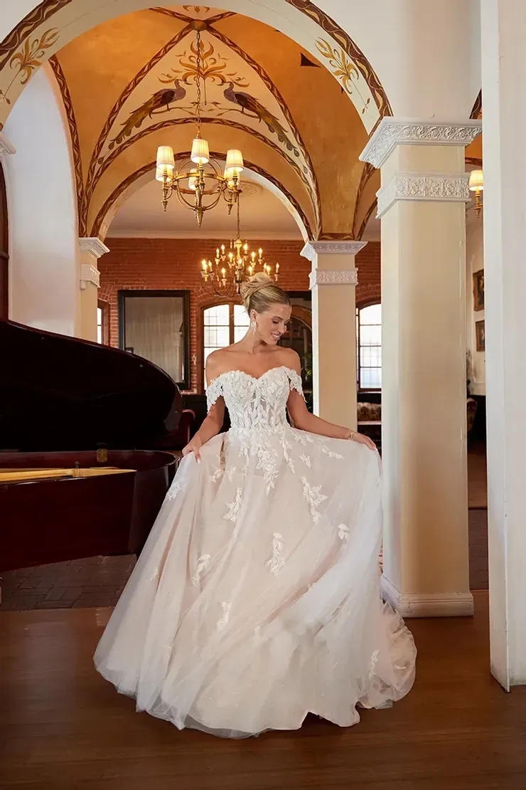 A woman in a wedding dress is standing in a room next to a piano.