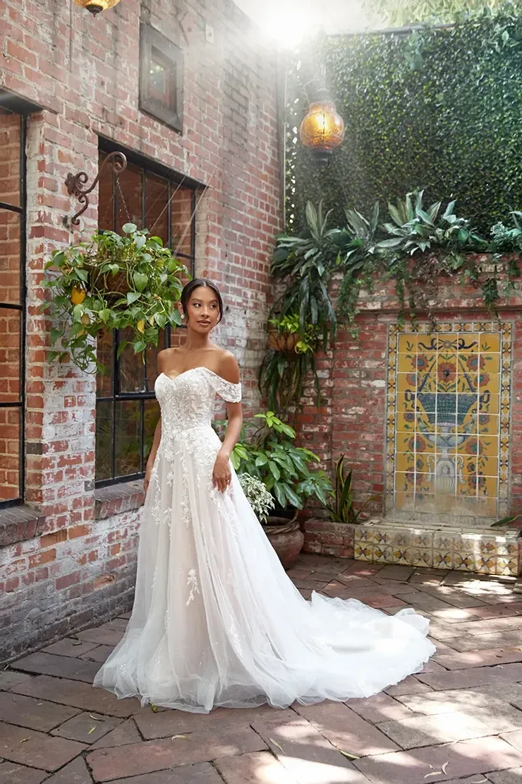 A woman in a wedding dress is standing in front of a brick building.