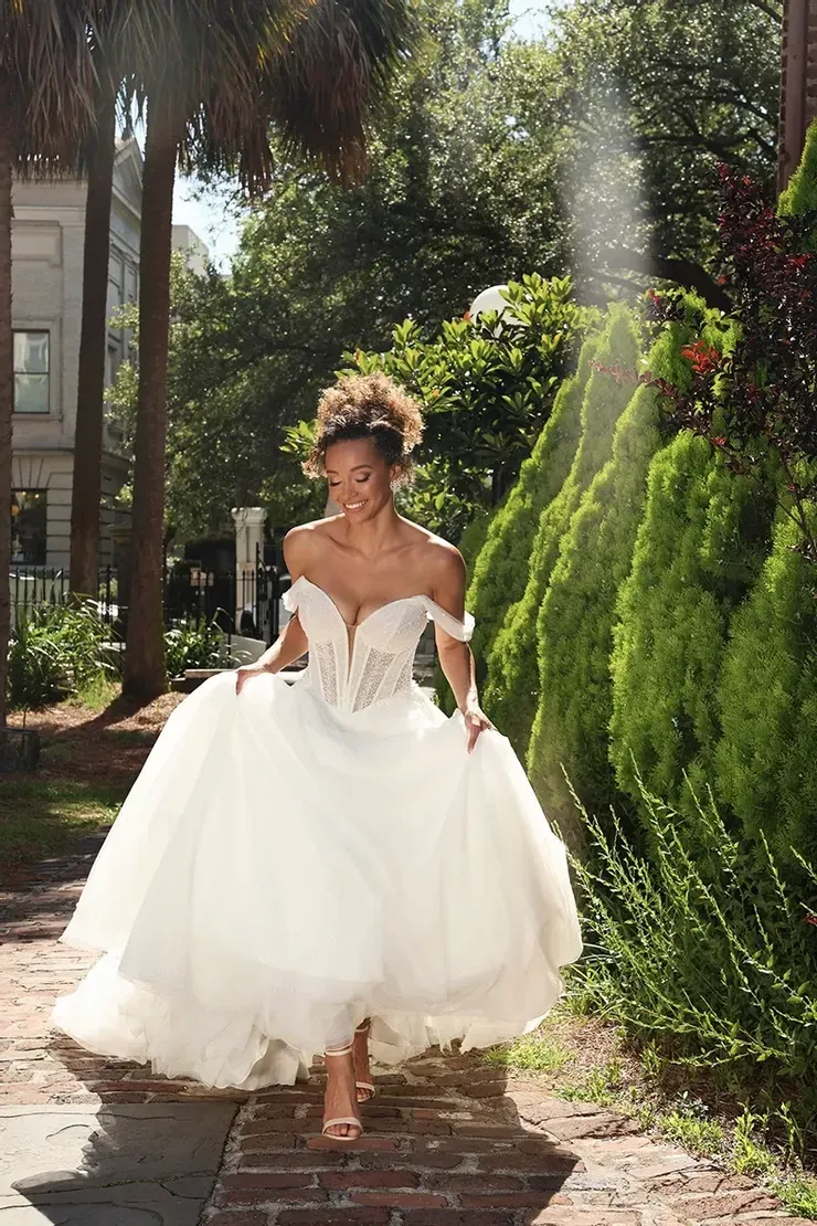 A woman in a wedding dress is walking down a sidewalk.