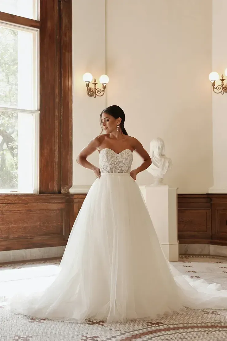 A woman in a white wedding dress is standing in a room.