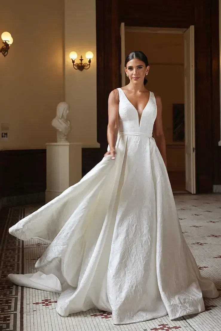 A woman in a white wedding dress is standing in a hallway.