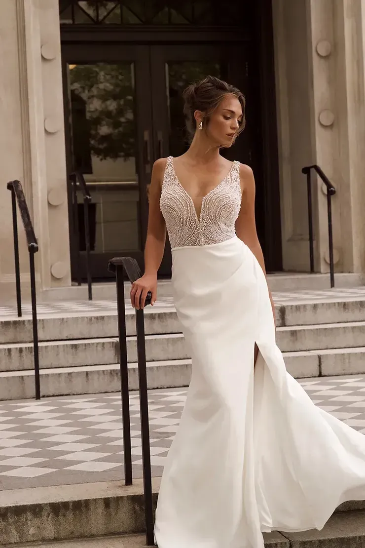 A woman in a white wedding dress is standing on a set of stairs.