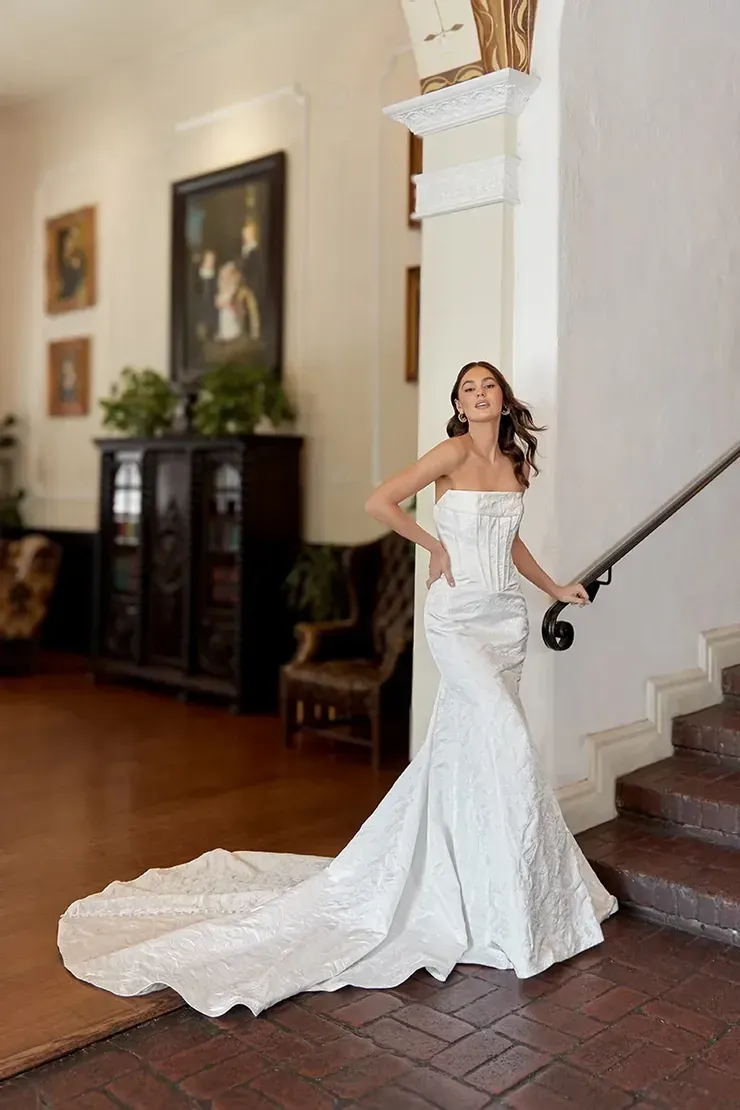A woman in a white wedding dress is standing on a set of stairs.