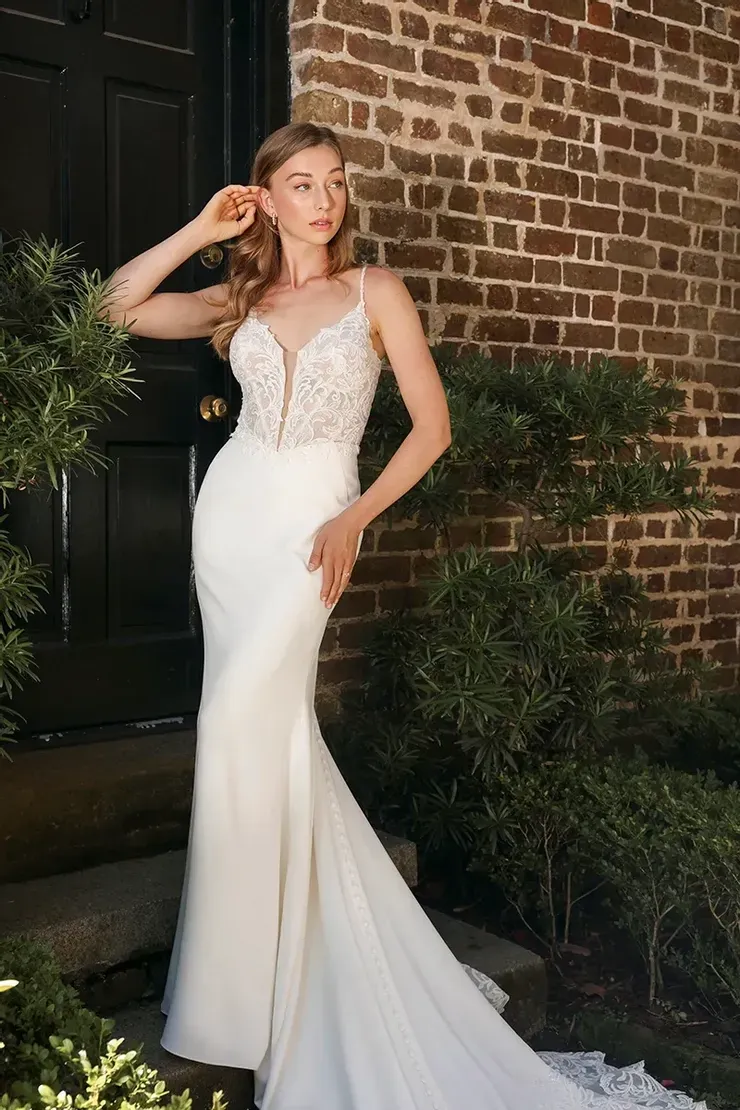 A woman in a wedding dress is standing in front of a brick building.