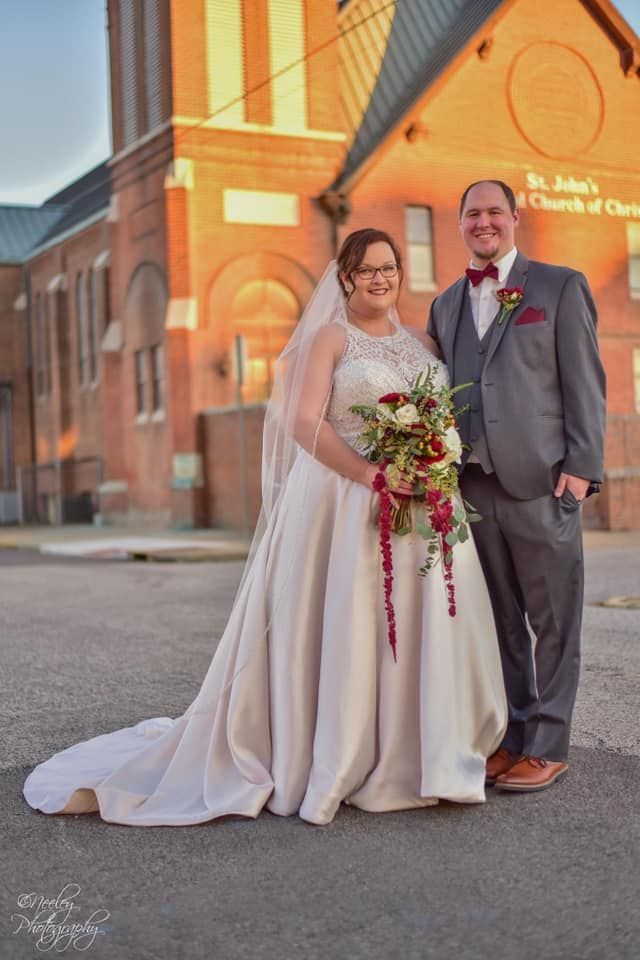 A bride and groom are posing for a picture in front of a church.