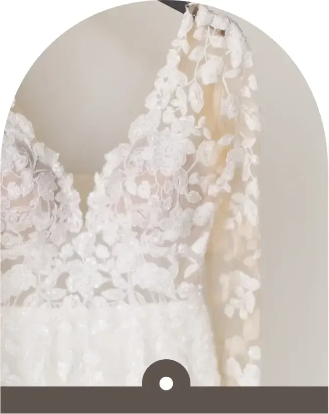 A white lace wedding dress is hanging on a hanger.