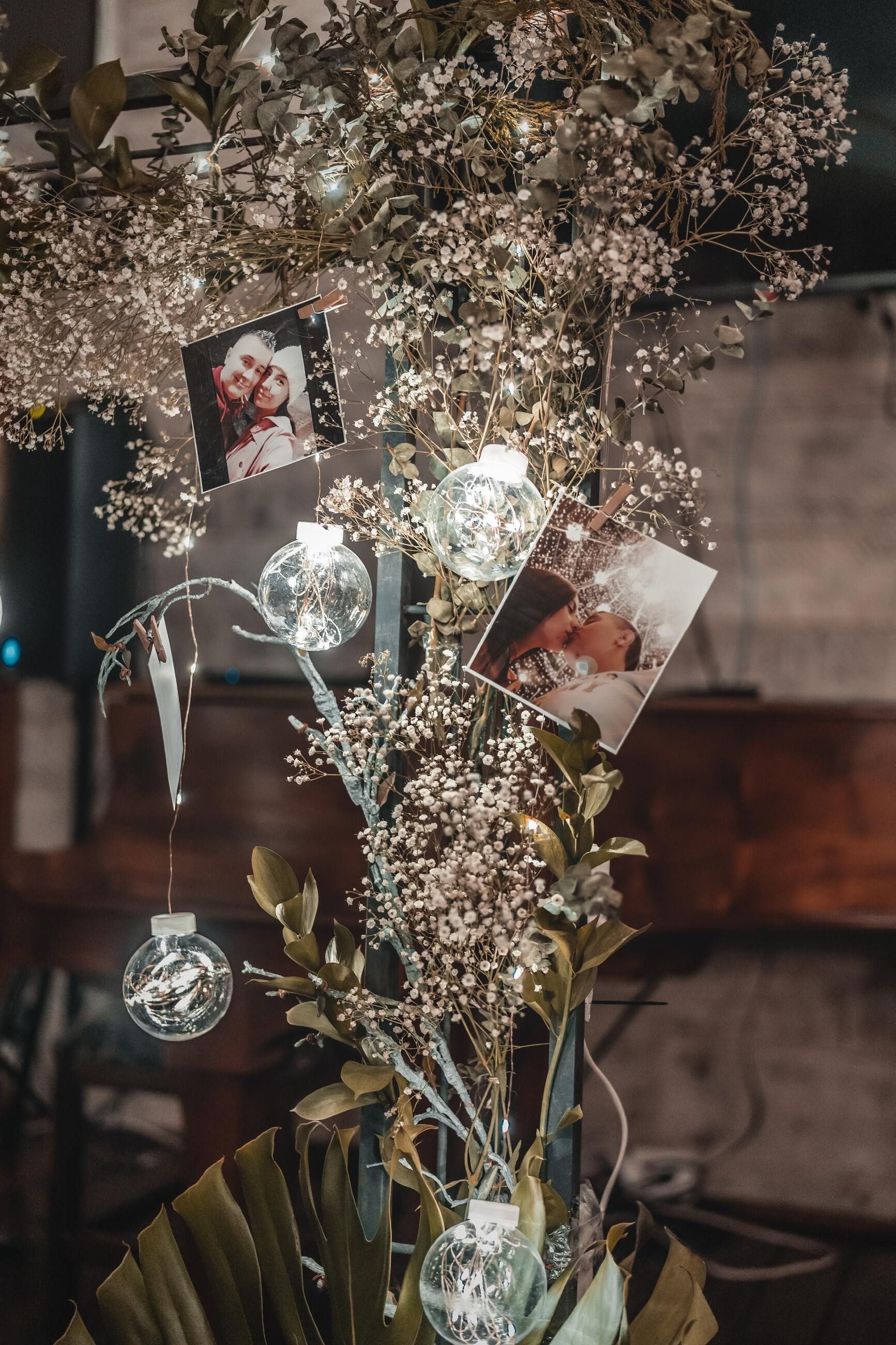 A tree with baby 's breath , lights , and pictures hanging from it.