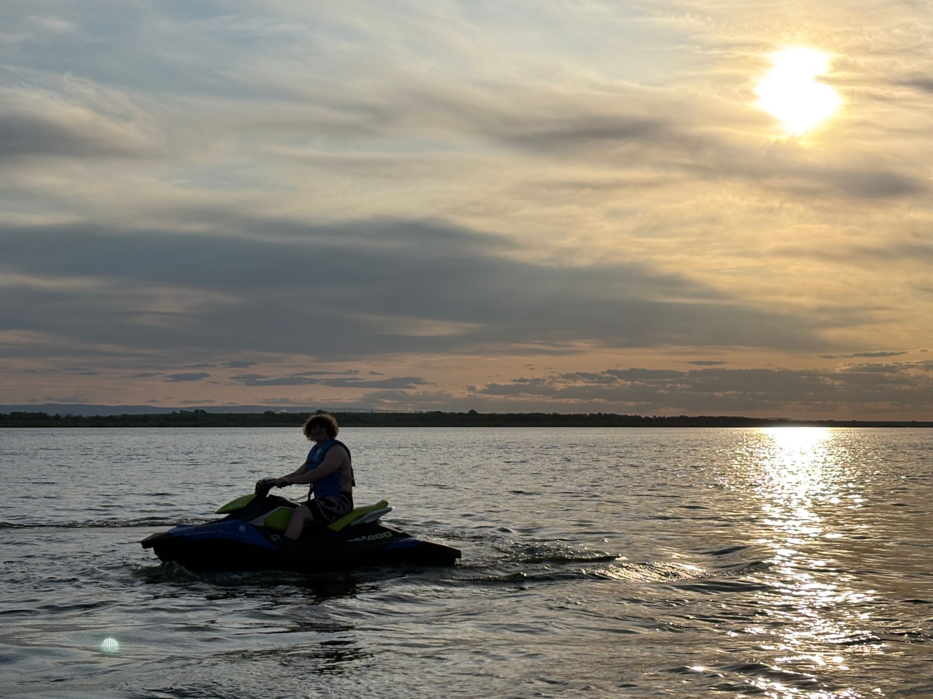 A man is riding a jet ski in the water at sunset