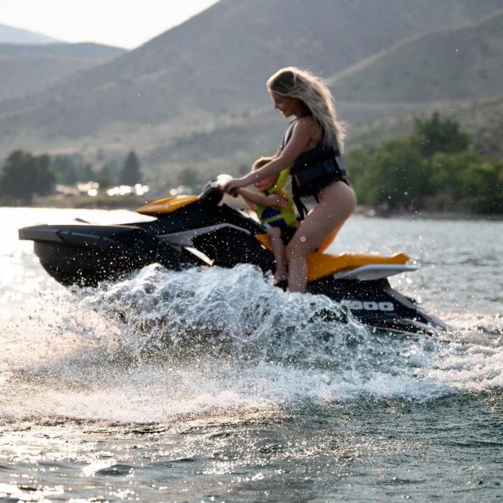 A woman is riding a jet ski with a child on it