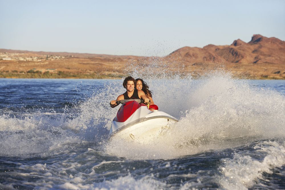A man and a woman are riding a jet ski on a lake.