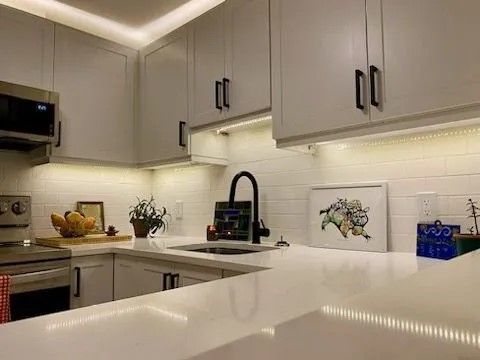 Modern white kitchen cabinet painting project in Halifax with updated hardware and under-cabinet lighting