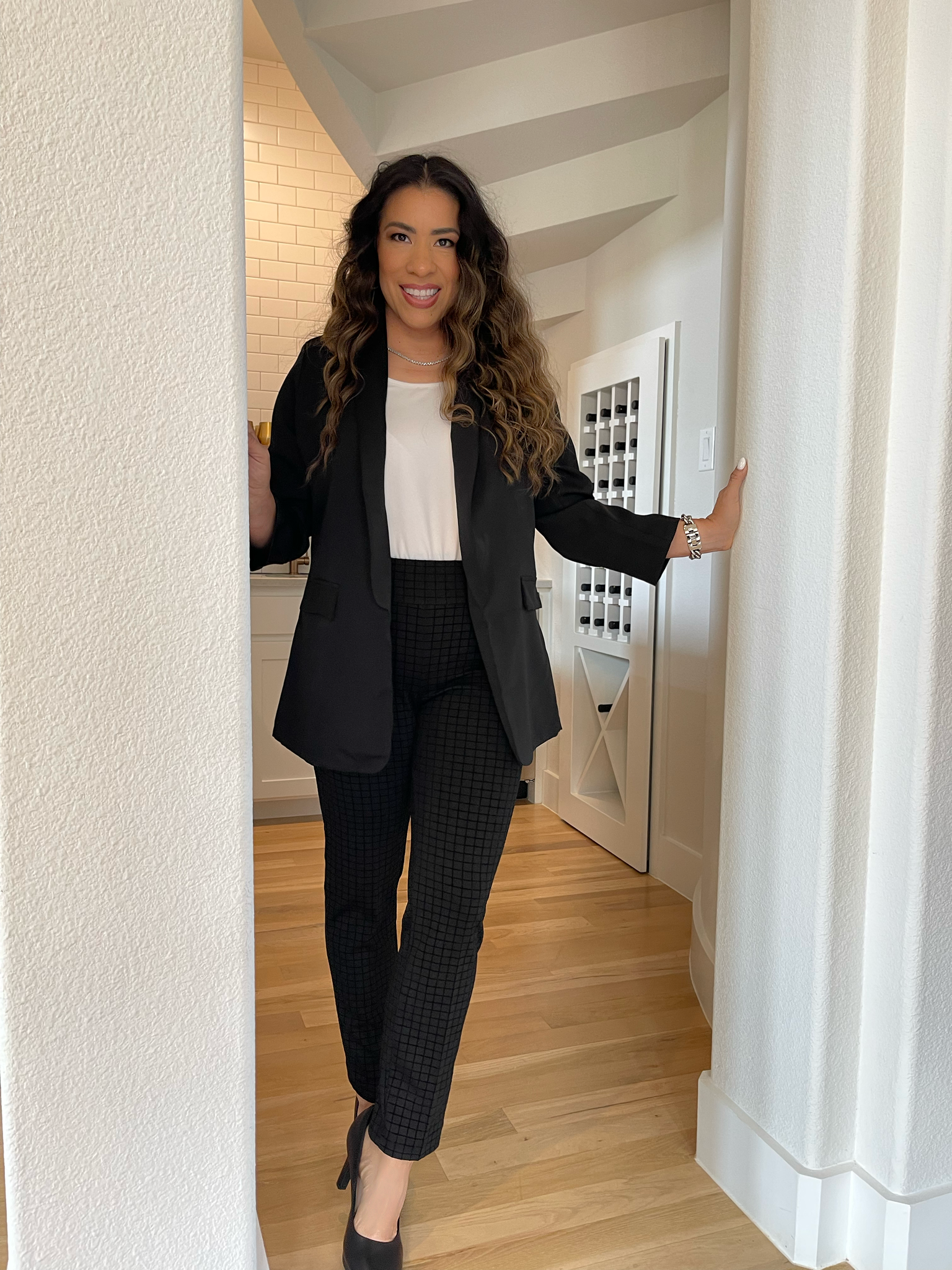 A woman is sitting at a desk with a laptop and a vase of flowers.
