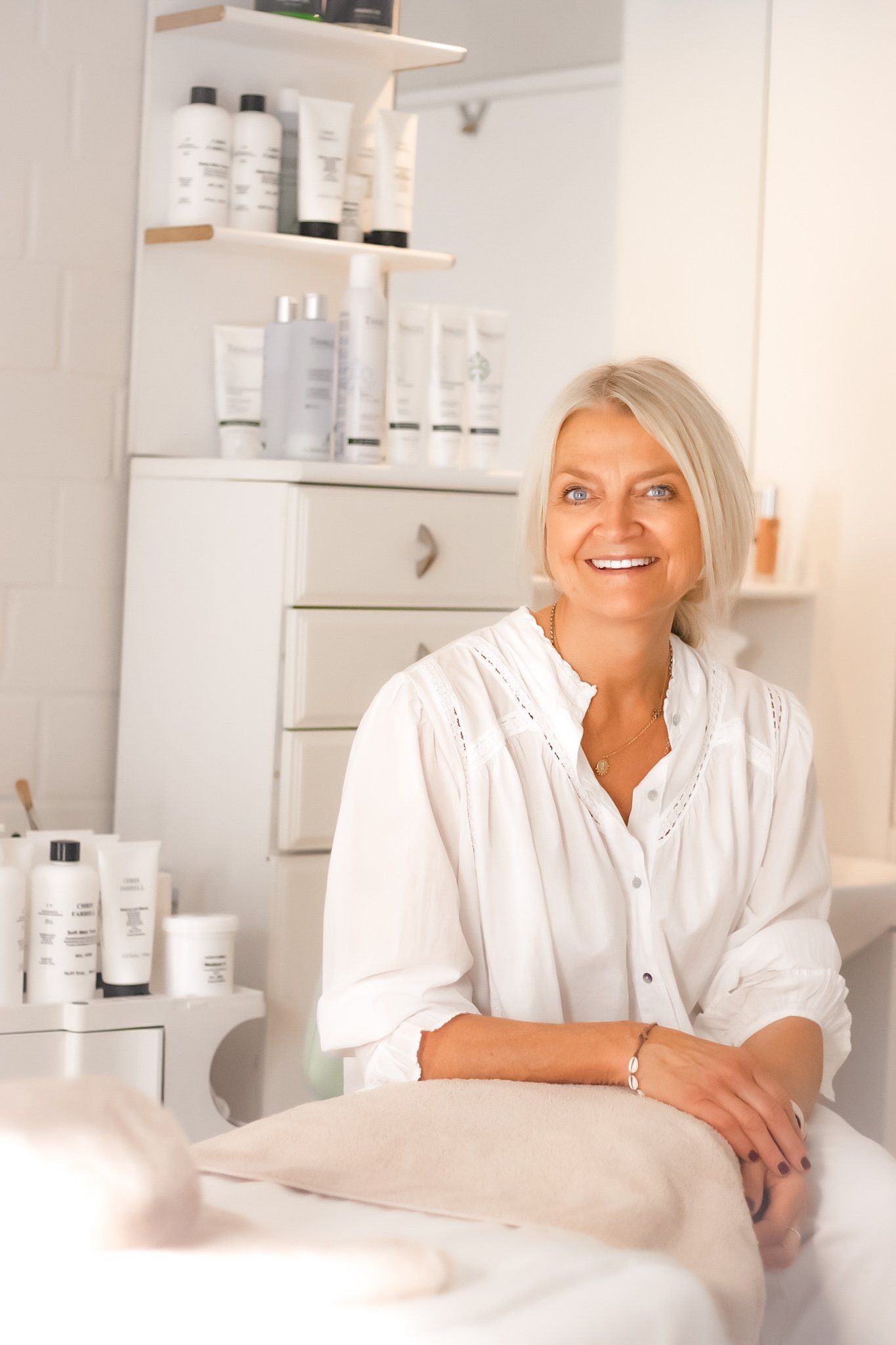 Eine Frau in einem weißen Hemd sitzt auf einem Bett in einem Salon.