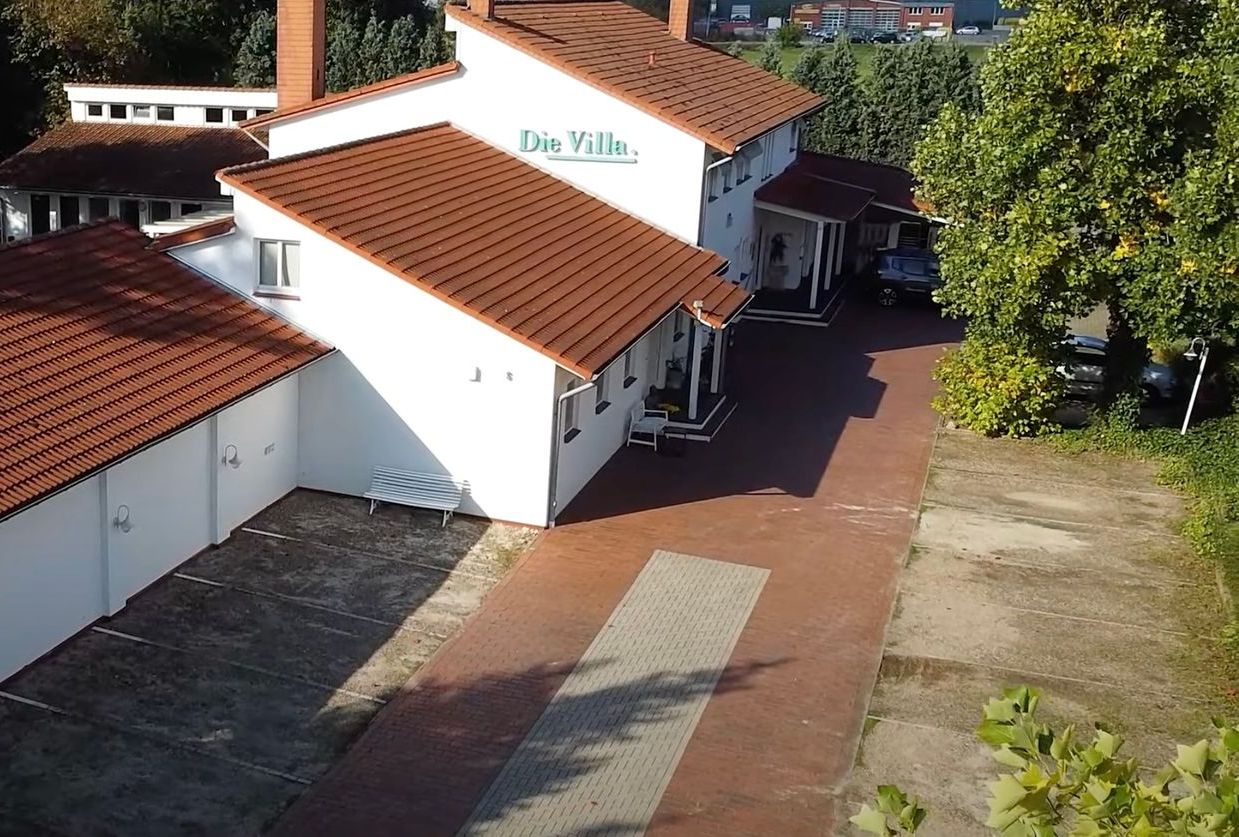 Eine Luftaufnahme eines weißen Gebäudes mit einem roten Ziegeldach