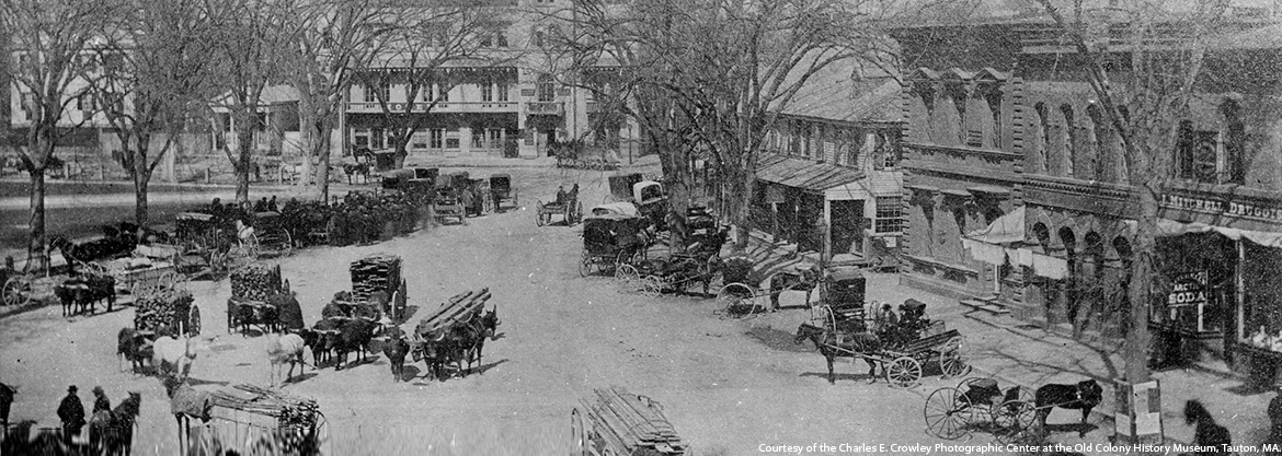a black and white photo of a city street with horse drawn carriages .