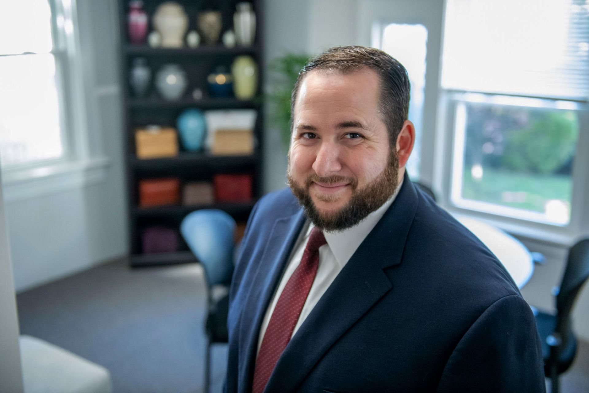 a man in a suit and tie is standing in a room in front of a window .