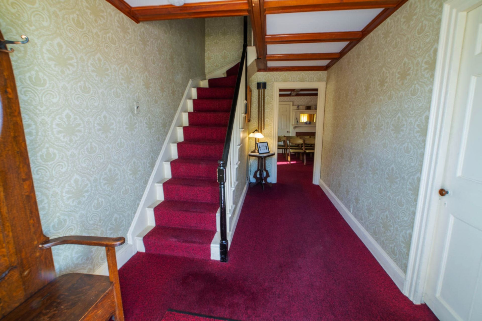 a hallway with red carpet and stairs in a house