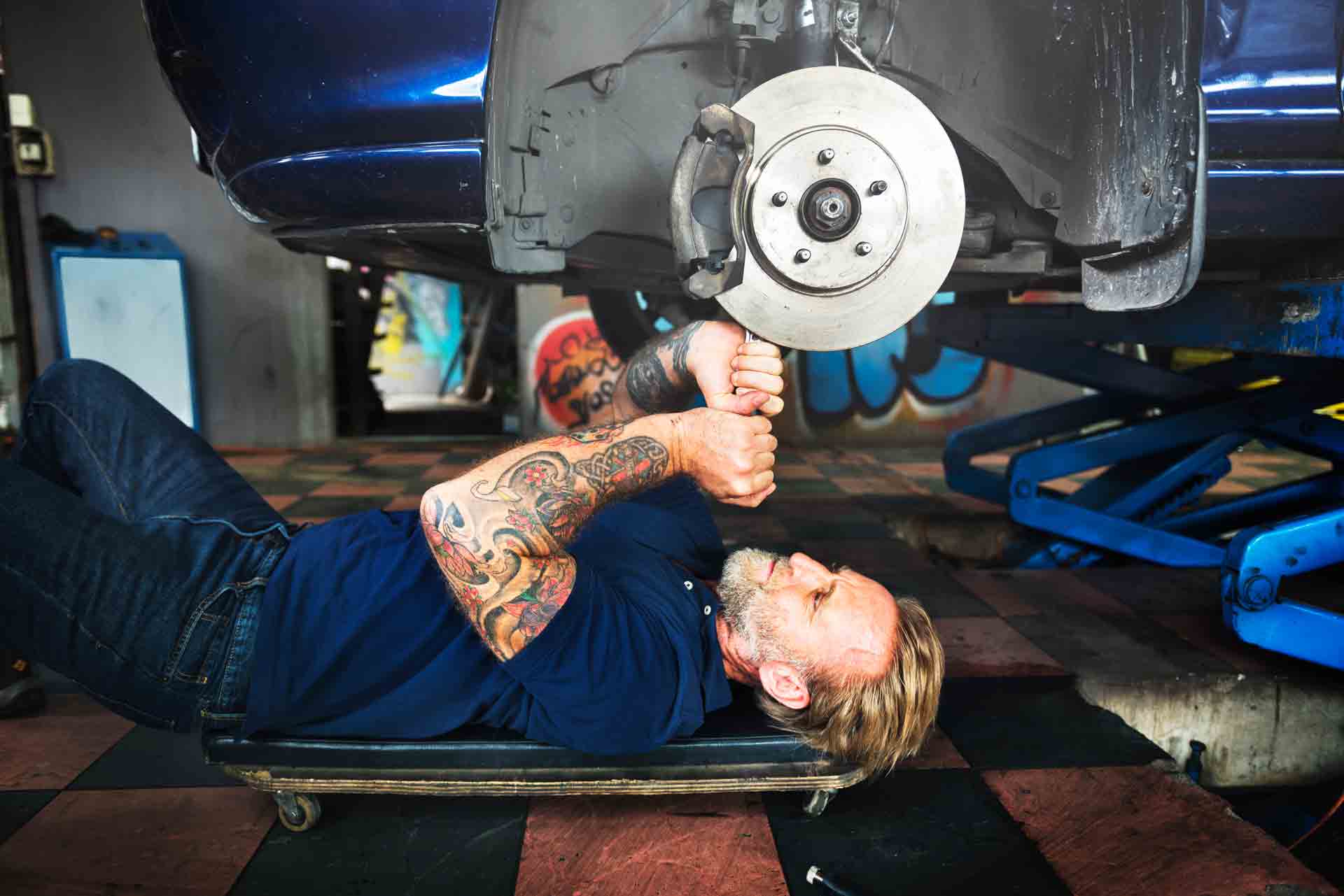 an employee laying underneath a car fixing the brakes