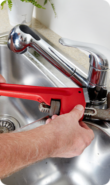 A red wrench being used on a tap