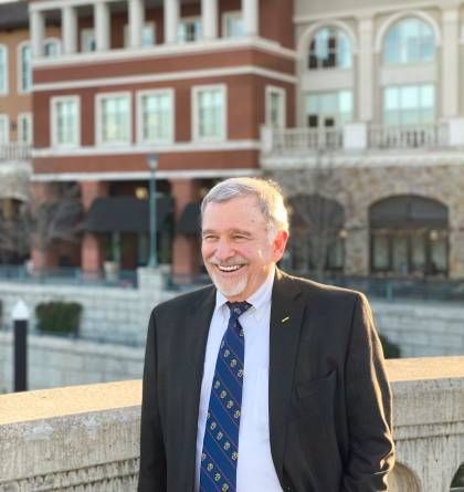 A man in a suit and tie is smiling in front of a building.