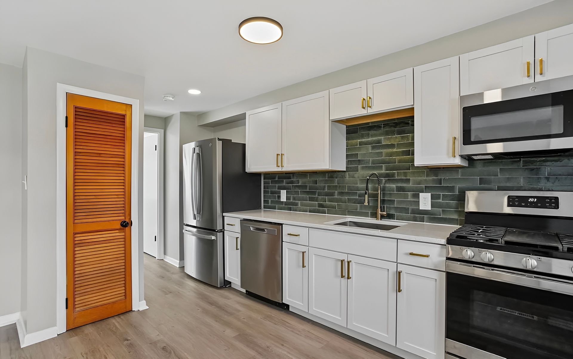 Kitchen renovation before and after. Updated kitchen with stainless steel appliances, new flooring, and light grey walls.