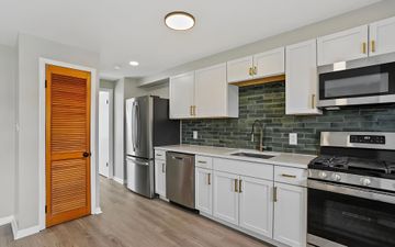 Kitchen renovation before and after. Updated kitchen with stainless steel appliances, new flooring, and light grey walls.