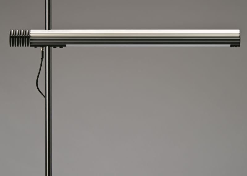 Eine Nahaufnahme einer Lampe auf einem Ständer vor grauem Hintergrund.