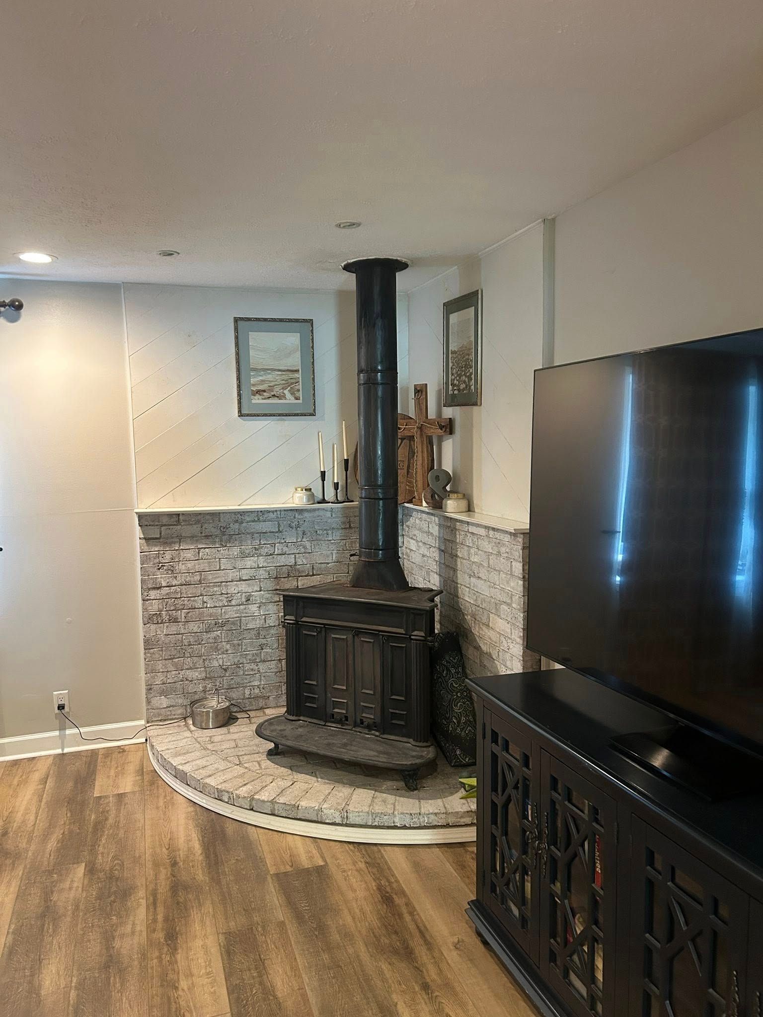 A black wood-burning stove on a brick hearth, flanked by white brick.
