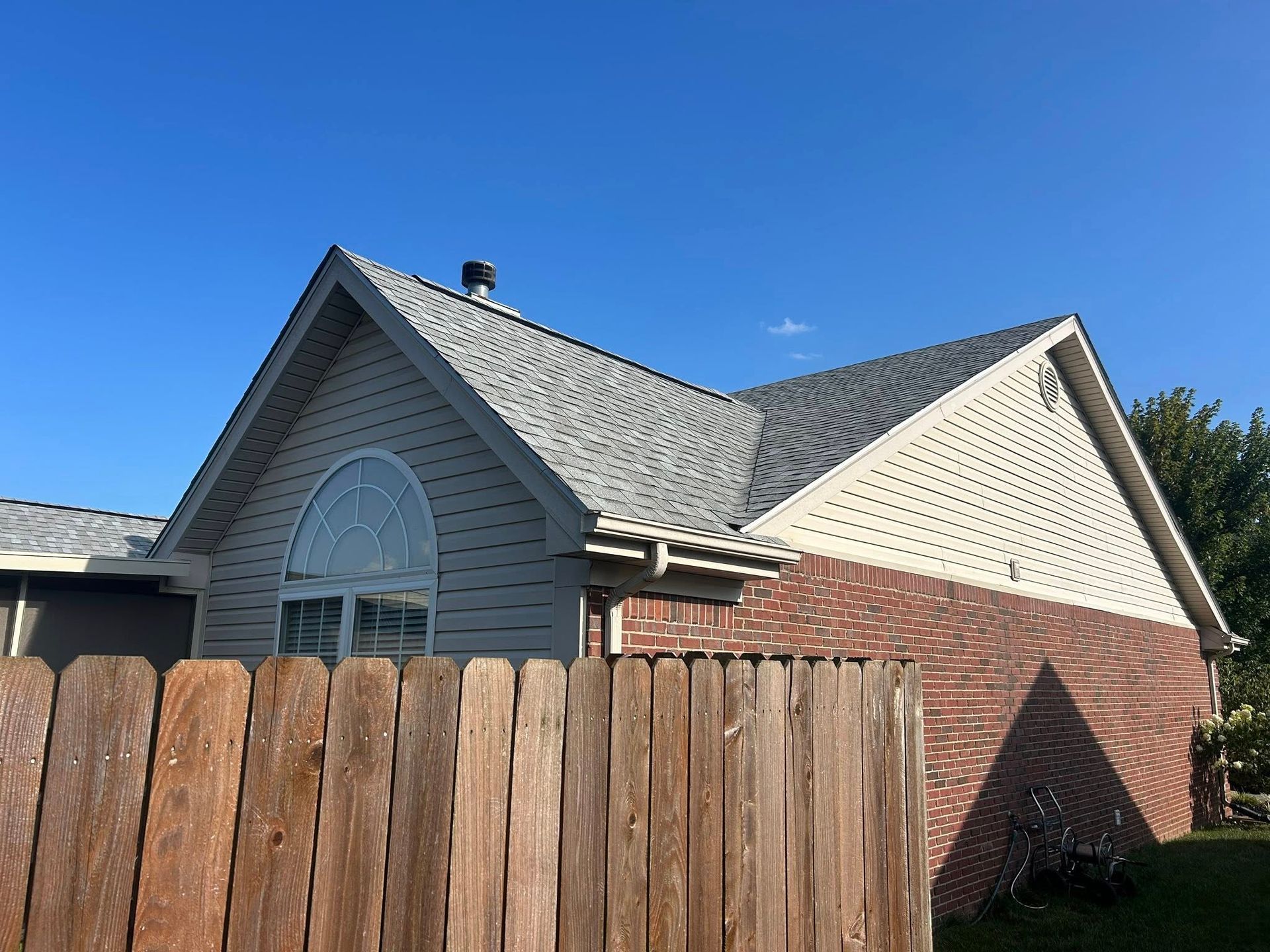 A house with a gray roof and brick and beige siding.