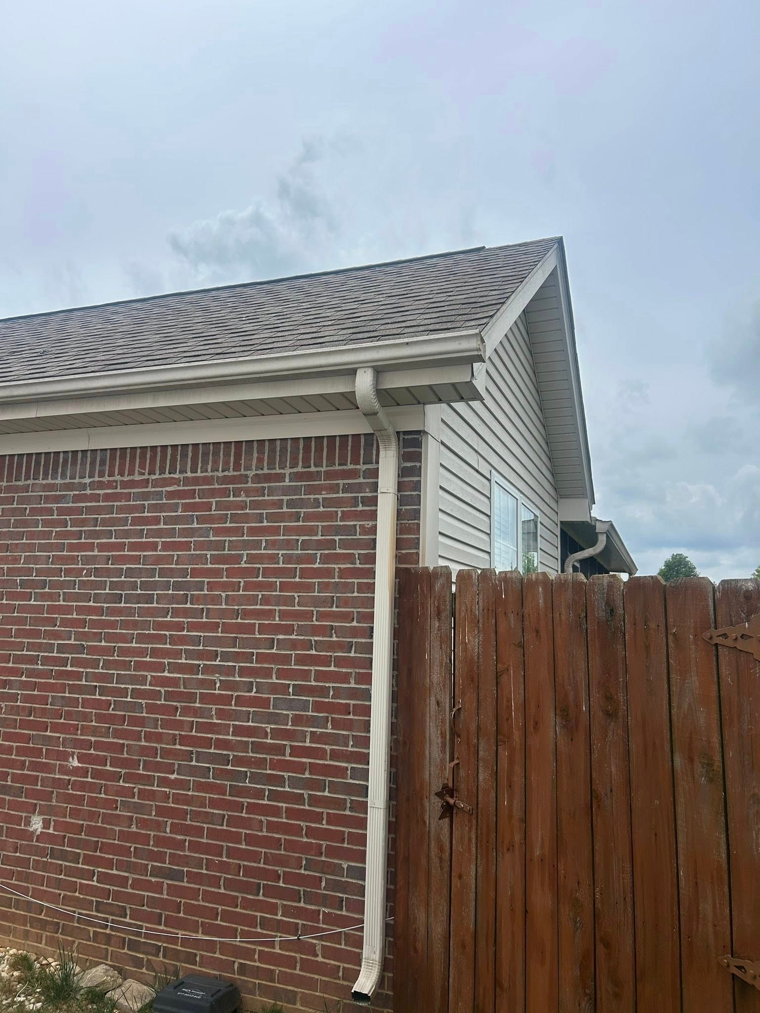 Brick building with brown roof, white trim, and a wooden fence.
