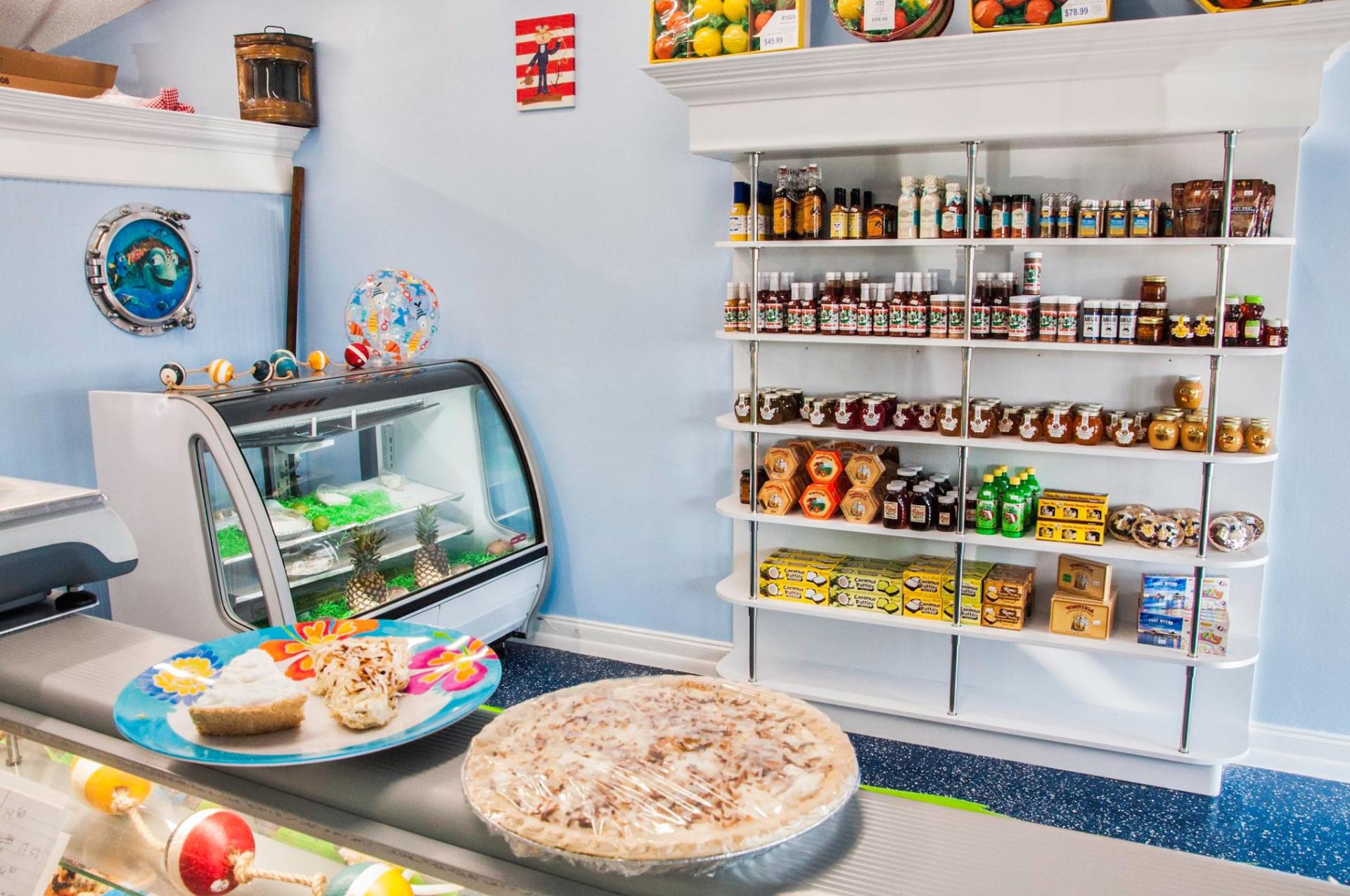 Interior of a shop displaying desserts, shelves of jars, and a refrigerated display case.