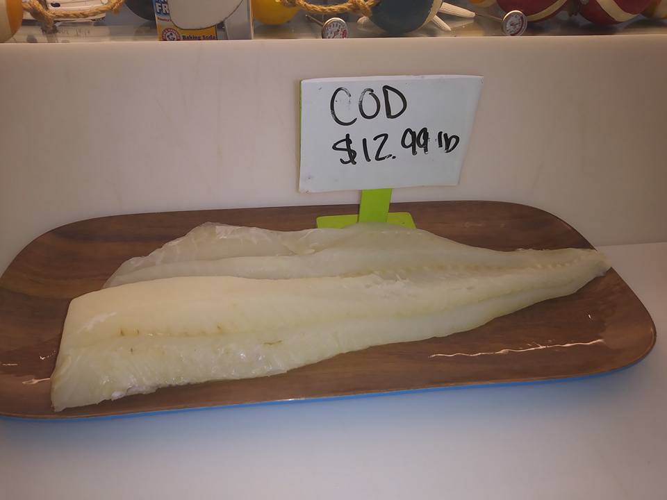 Cod fillets on a wooden plate, priced at $12.99 per pound.