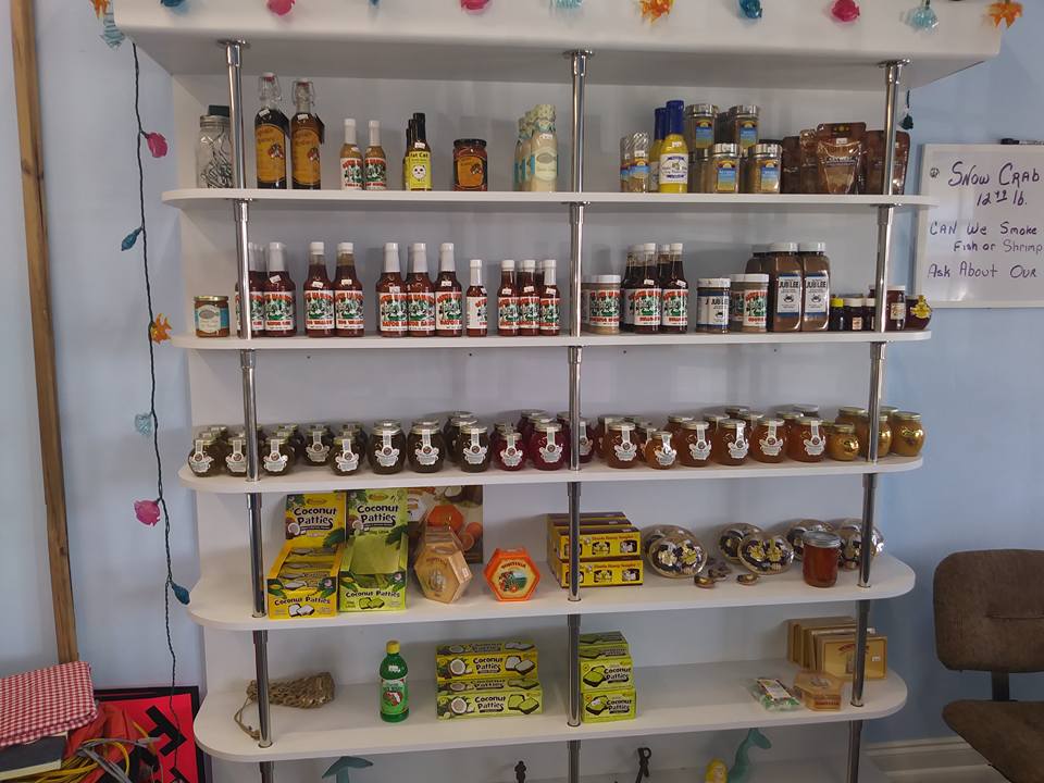 White shelves stocked with jars and bottles of various food products in a shop.