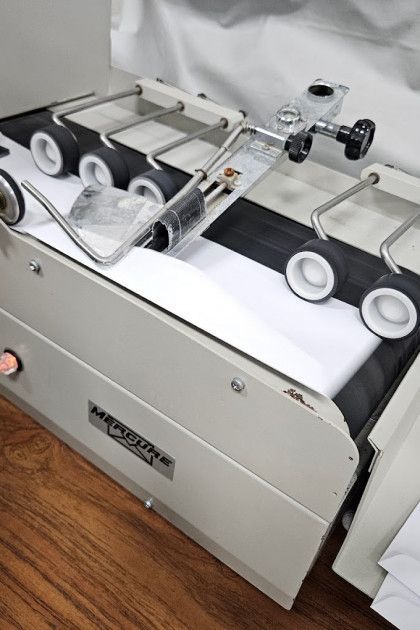 White and beige tabletop paper folding machine with rollers