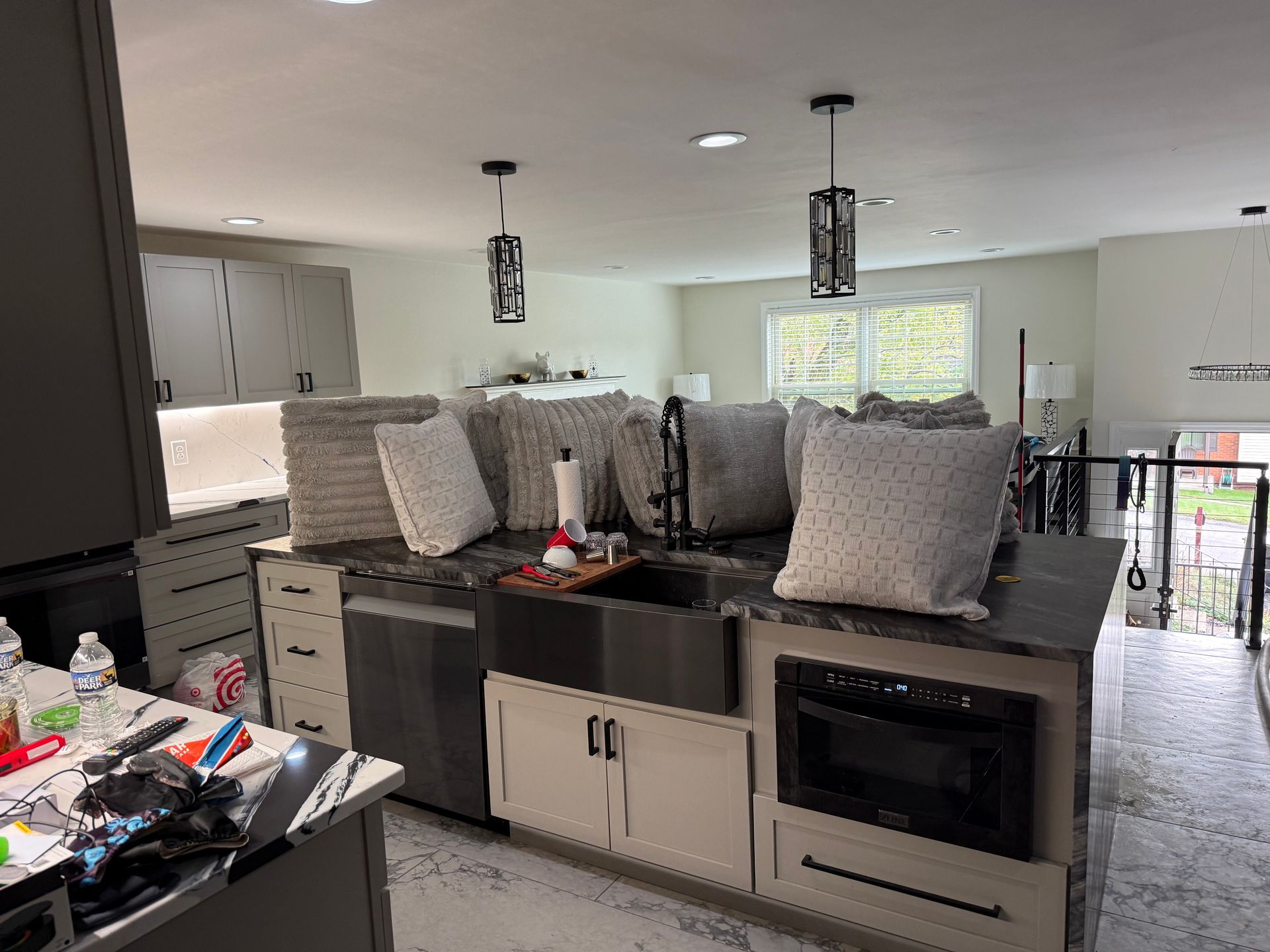 Kitchen with island, sink, microwave, and pendant lights. Light cabinets, gray countertops, and gray walls.