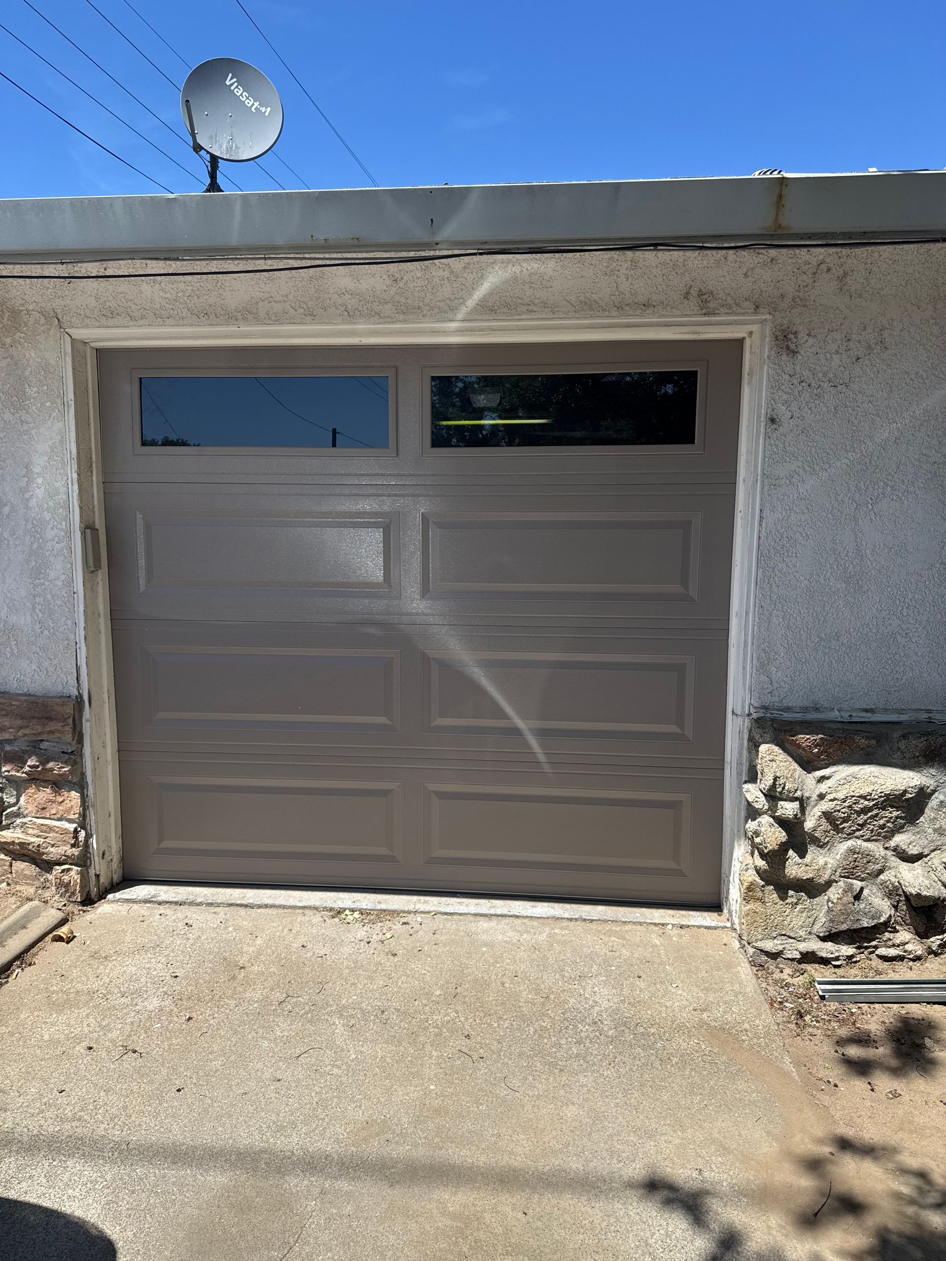 A garage door with a window and a satellite dish on top of it.