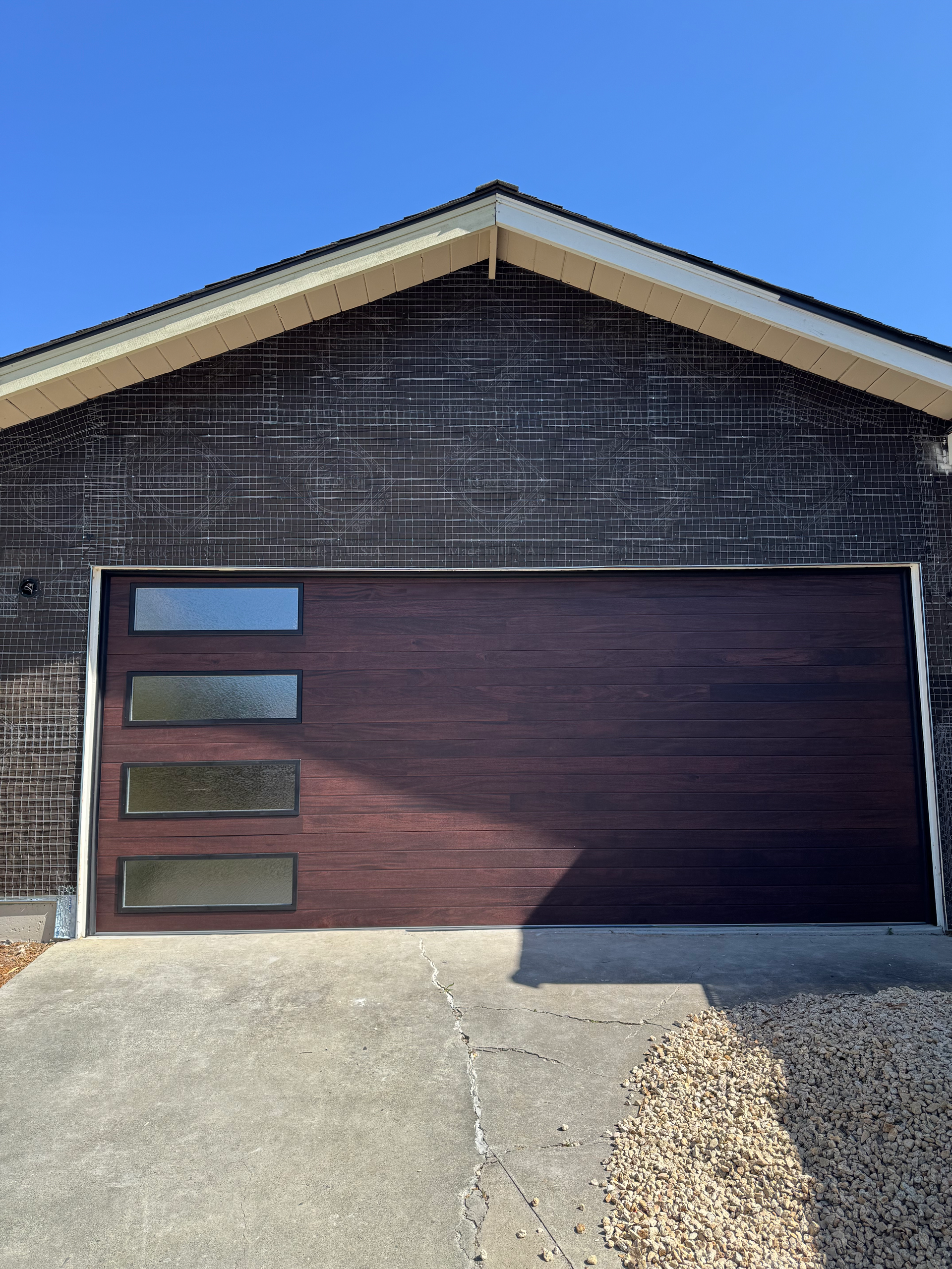 A brown garage door is sitting in front of a brick house.