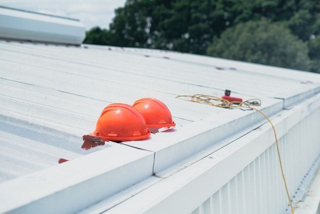 two orange hardhats on a white roof next to the gutters