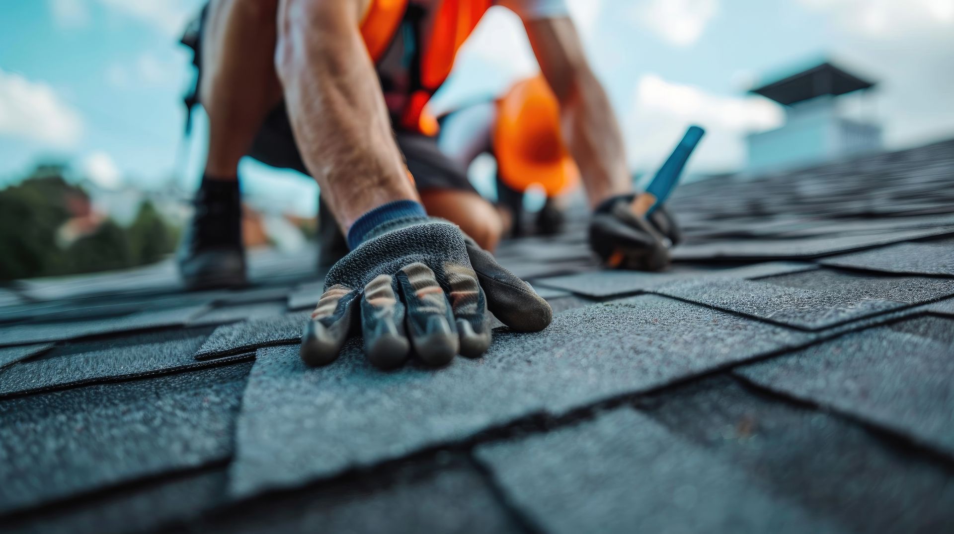 Roofing worker installing shingles with gloves and tools on a sloped roof. Roofing worker installing shingles with gloves and tools on a sloped roof.