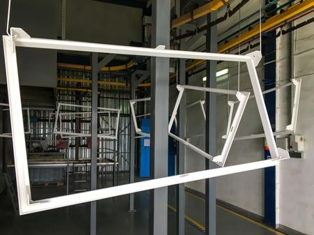 A white metal frame is hanging from the ceiling in a factory.