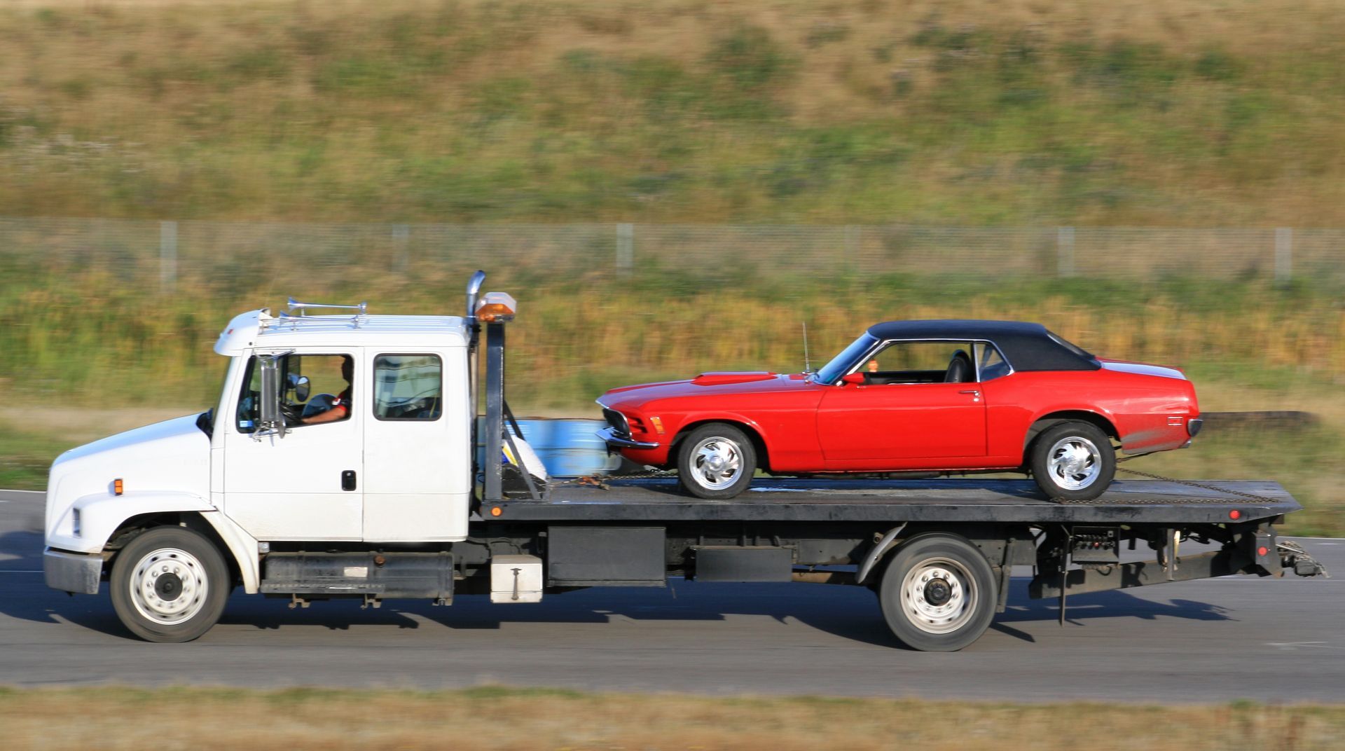 A silver car is being towed by a white truck.