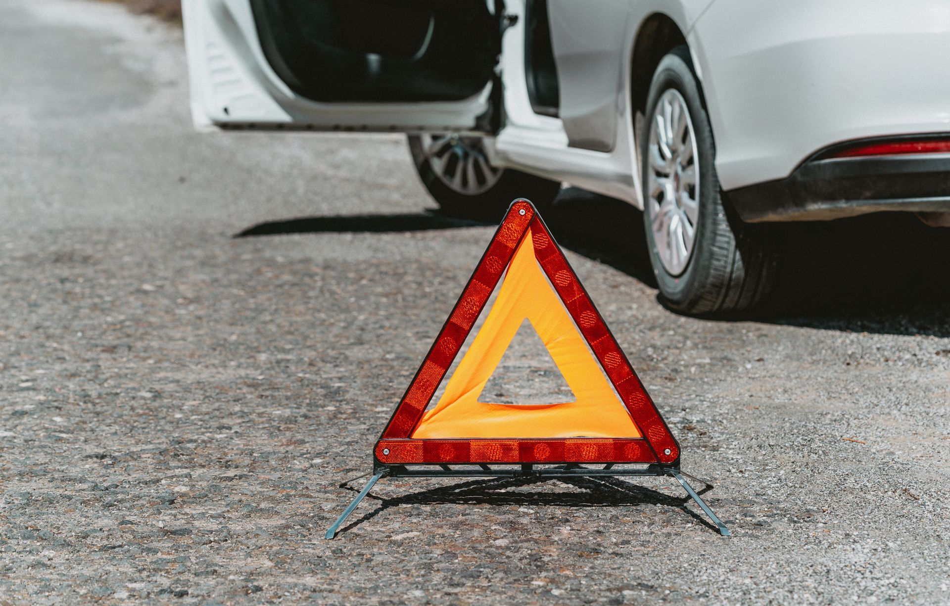 A warning triangle is sitting on the side of the road next to a car.